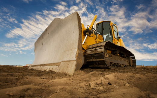 A large yellow bulldozer at a construction site low angle view