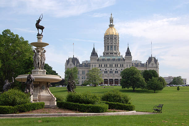 A fountain and park at Hartford Hartford, Connecticut state capitol building photographed from Bushnell Park. The historic Corning Fountain is in the foreground.  connecticut state capitol building stock pictures, royalty-free photos & images