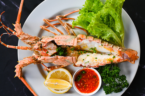 spiny lobster food on plate, fresh lobster or rock lobster seafood with herb and spices lemon coriander parsley lettuce salad, lobster for cooking food and seafood sauce