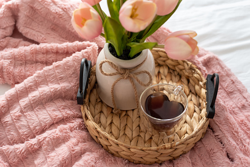 Cozy cup of tea in a heart shaped cup on a tray with pink flowers