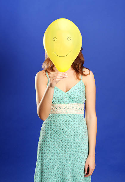 istock girl holding yellow smiling balloon 147687522
