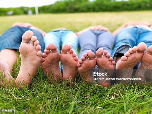 Feet Of Teenagers Lying On Green Grass In A Field Stock Photo - Download Image Now - Sole Of Foot, Teenager, Public Park