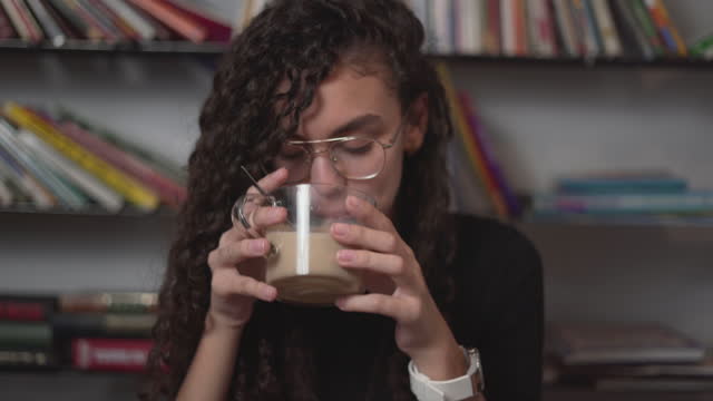 Girl Stirring Hot Coffee On Wooden Table And Then Smelled It. - close up