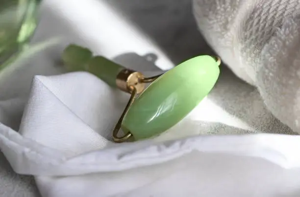 Gua sha or jade facial roller iwith white towel for home massage .