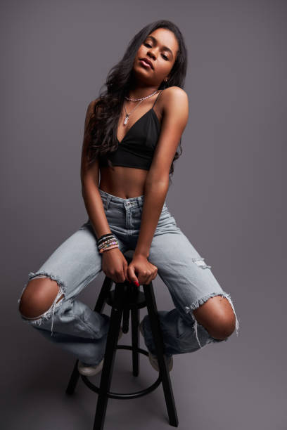 istock Self assured young Hispanic woman relaxing on stool in gray studio 1476888667