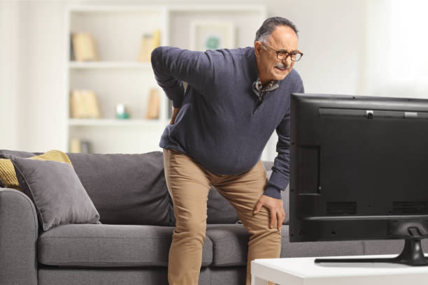 istock Mature man with back pain trying to sit on a sofa 1476894735