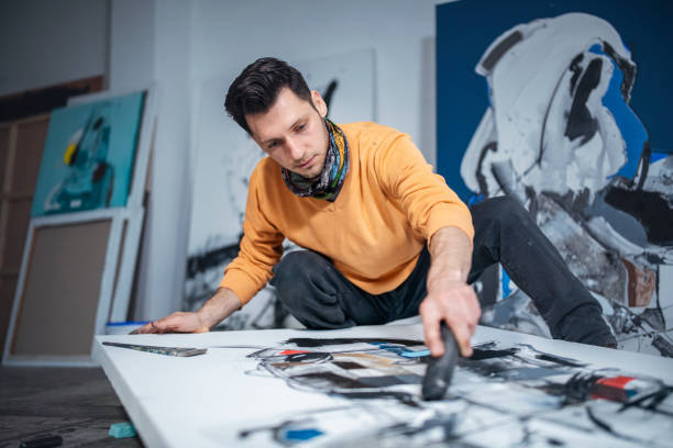 istock Artist working on his painting in art studio. 1476896207