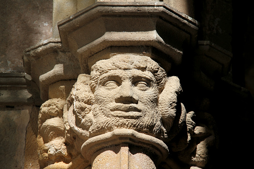 A column with faces carved into into in Barcelona.