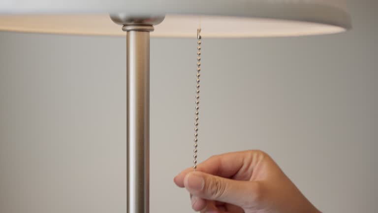 Hand pulling a chain switch for turning off the room lamp lighting equipment