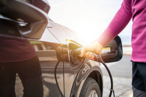 istock Midsection of man plugging cable in electric car. 1476903580