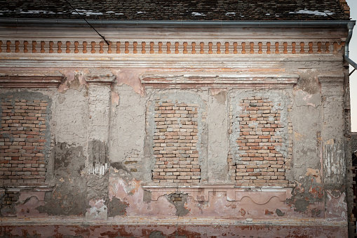 Picture of an abandoned farm in Vojvodina, in Serbia, with the facade of its main house being heavily damaged and decaying with walled up, bridked up and boarded windows