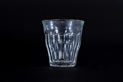 Picture of an isolated duralex picardie tumbler class in front of a black background. The Duralex Picardie is a classic design of a toughened glass tumbler found in cafes, schools and homes across France and in many places worldwide.