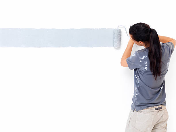 vista lateral de la espalda de una mujer pintar la pared - female house painter home decorator paintbrush fotografías e imágenes de stock