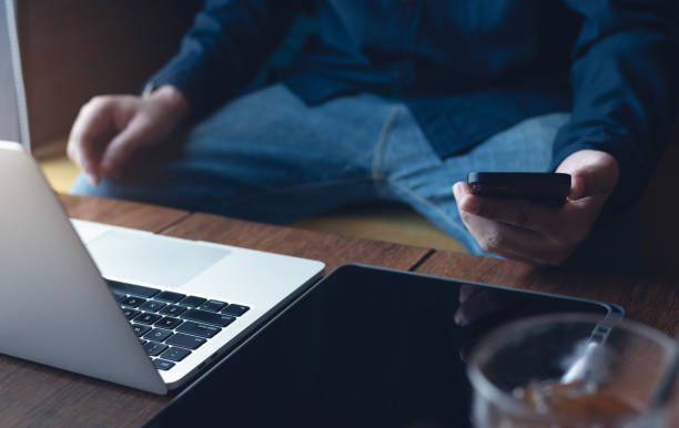 istock Man freelancer working on laptop and using mobile phone on wooden table at coffee shop, telecommuting 1476916489