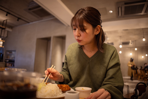 Young woman eating pork cutlet for lunch in cafe