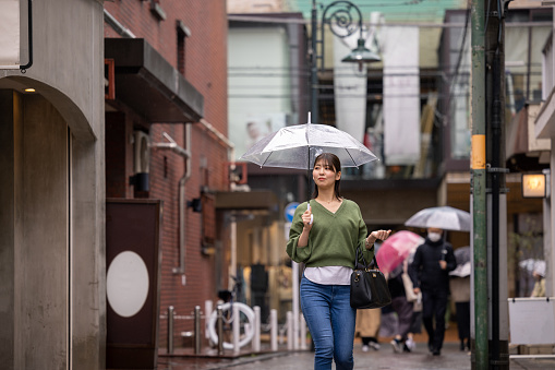 Young woman walking in shopping street in a rainy day