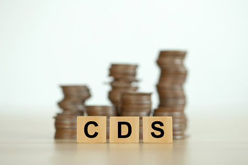 text CDS written on wooden cubes in front of the coins stack. It is an abbreviation for credit default swap. a financial derivative that allows an investor to swap his credit risk.credit default swap
