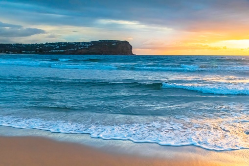 Sunrise seascape with rain clouds and rocks at Macmasters Beach on the Central Coast, NSW, Australia.