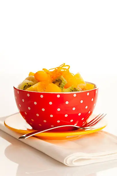 Fruit salad on the white dotted bowl (kiwi, orange, pinapple, banana etc).