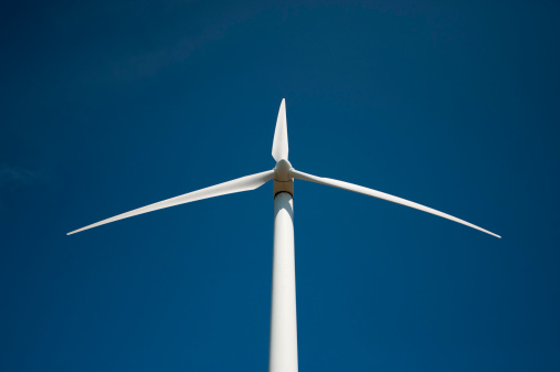 A wind turbine set against a deep blue afternoon sky.
