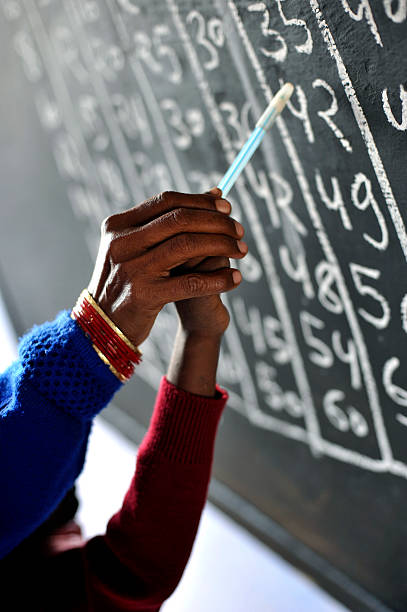 India school School in India. Teacher helping a pupil with numbers on the blackboard. number 42 stock pictures, royalty-free photos & images