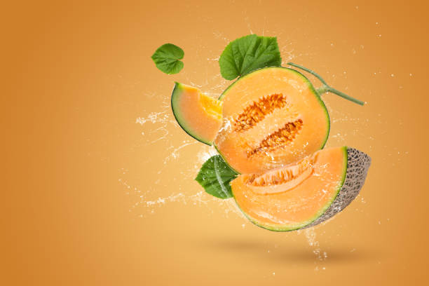 salpicaduras de agua enteras y rodajas de melón japonés naranja o melón cantaloupe con semillas sobre fondo naranja - splashing orange fruit water fotografías e imágenes de stock