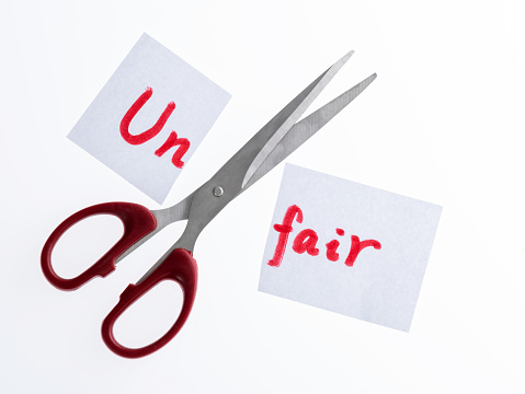 Scissor cutting paper with word unfair
