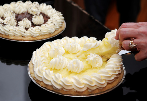 A lady serving banana cream pie