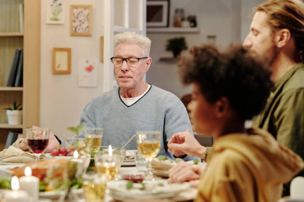 istock Focus on aged man with grey hair praying by served festive table 1476966515