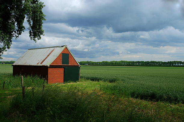 旧バーンのフィールドに嵐の空 - barn red old door ストックフォトと画像