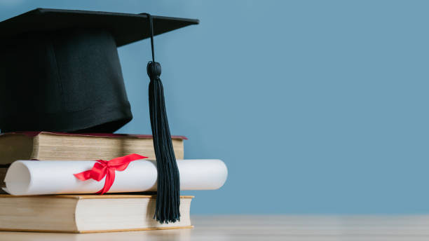 istock Graduation day.A mortarboard and graduation scroll on stack of books with blue background.Graduation day.Education learning concept. 1476976229