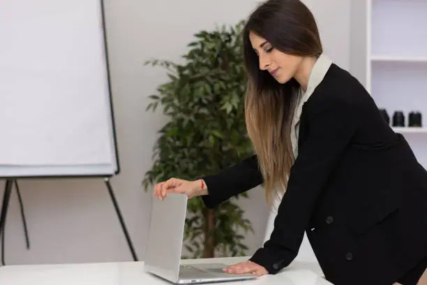 Office long hair brown hair young woman is closing her laptop