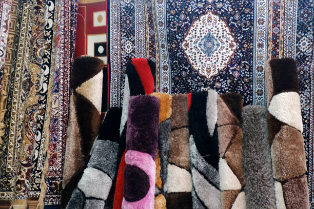 istock Stack of multicolored quality rugs at carpet shop, Carpets variety selection rolled up rugs shop store. 1476981688