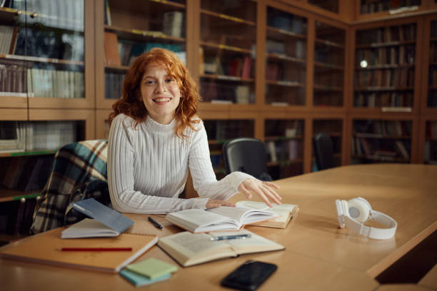 istock Happy female student enjoying while studying in library. 1476982168