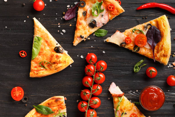 istock Pizza slices are laid out on a dark background top view. 1476983112