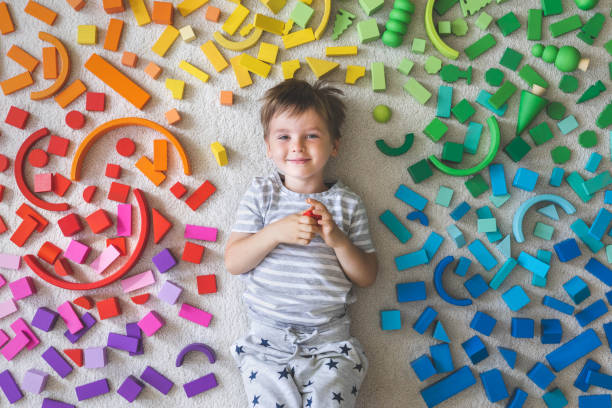 Wooden bricks Montessori material rainbow spectrum. Little cute boy plays with cubes. stock photo