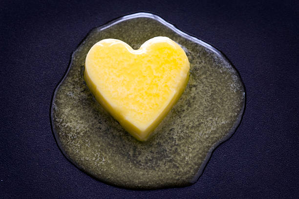 butter heart melting a heart shaped butter pat melting on a non-stick surface saturated fat stock pictures, royalty-free photos & images