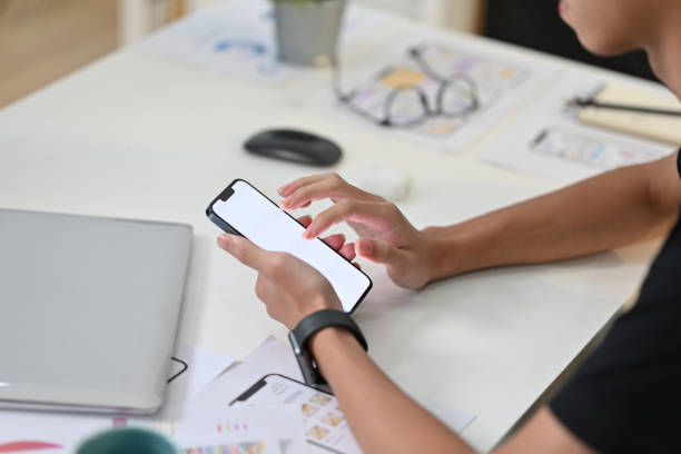 istock Side view of young creative man in casual clothes using smart phone at workstation. 1477012066