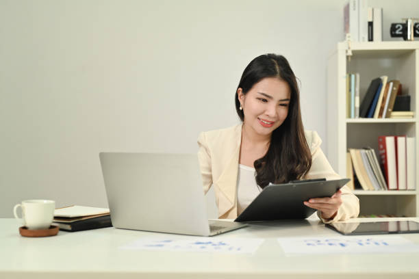 istock Concentrated female economist analyzing financial data and using laptop computer at work station. 1477013173