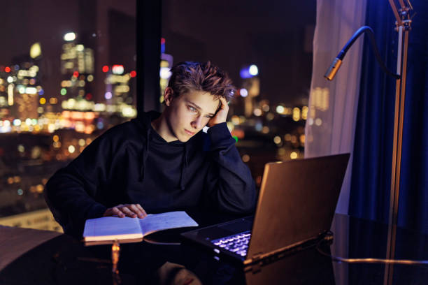 istock Teenage boy doing homework late at night 1477025433