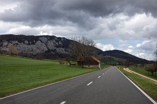 Country road and rural landscape in Jura Mountains, Swiss countryside.