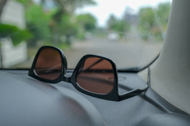 Sun glasses on the dashboard of a car parked on the side of the road. Sun glasses on the dashboard of a car parked on the side of the road. kacamata hitam stock pictures, royalty-free photos & images