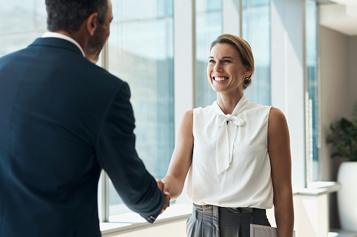 Handshake, meeting and business people partnership for b2b collaboration, onboarding welcome or professional opportunity. Corporate woman or clients shake hands for deal in office building interview