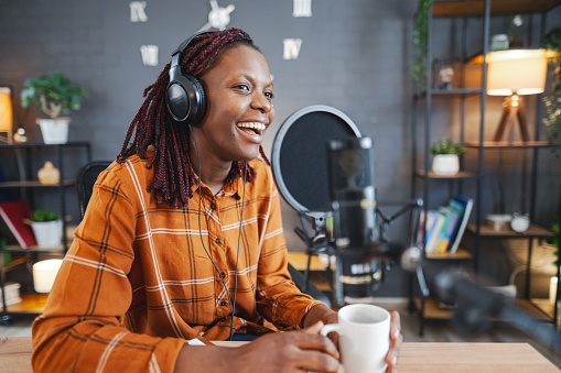 African woman recording podcast, talking on microphone