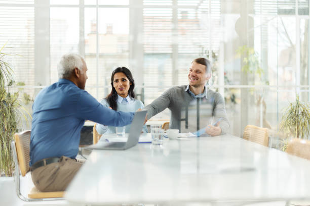 istock Happy diverse couple shaking hands with insurance agent in the office. 1477041221