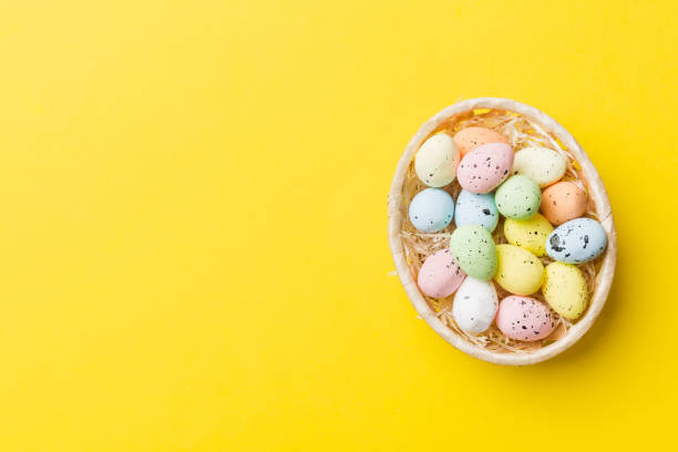 istock Colorful Easter eggs in wicker basket against colored background, closeup. top view with copy space 1477044410
