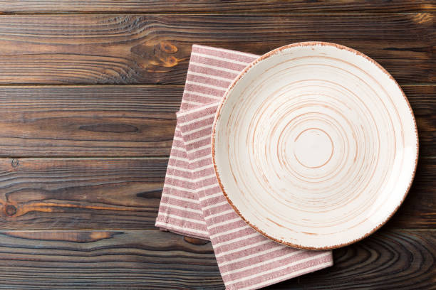 istock Top view on colored background empty round white plate on tablecloth for food. Empty dish on napkin with space for your design 1477044434