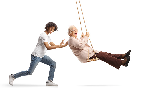 Young african american man pushing a caucasian senior woman on a swing isolated on white background