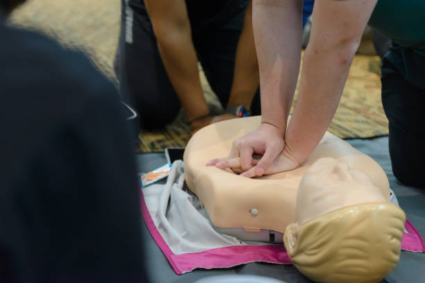 istock CPR First Aid Training with CPR dummy in the class. Demonstrating chest compressions concept. 1477046515