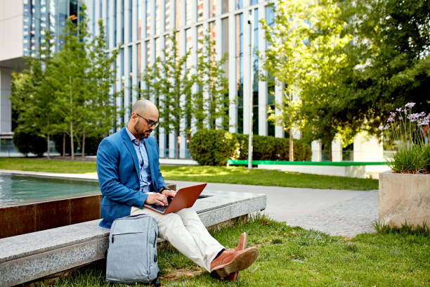 istock Mid 30s businessman using laptop outdoors 1477047685